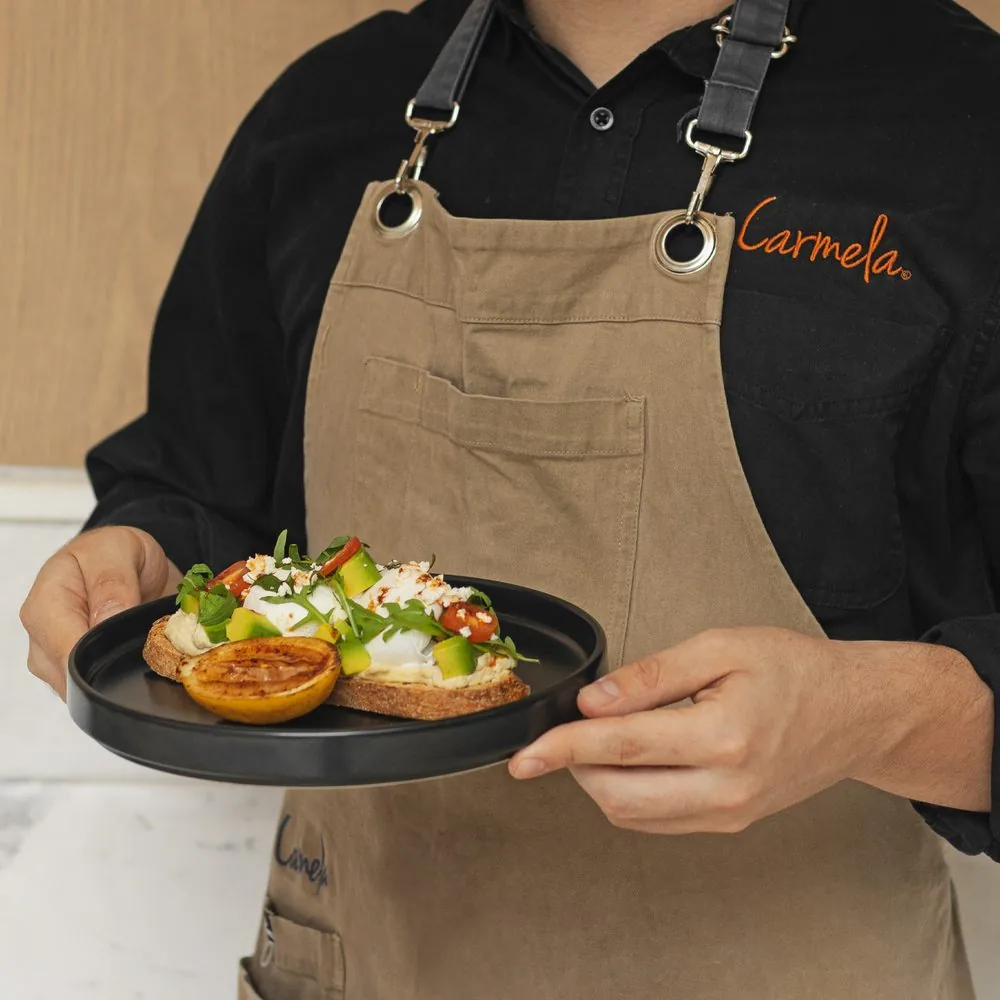 Mesero con el mandil de Carmela sirviendo una tosta