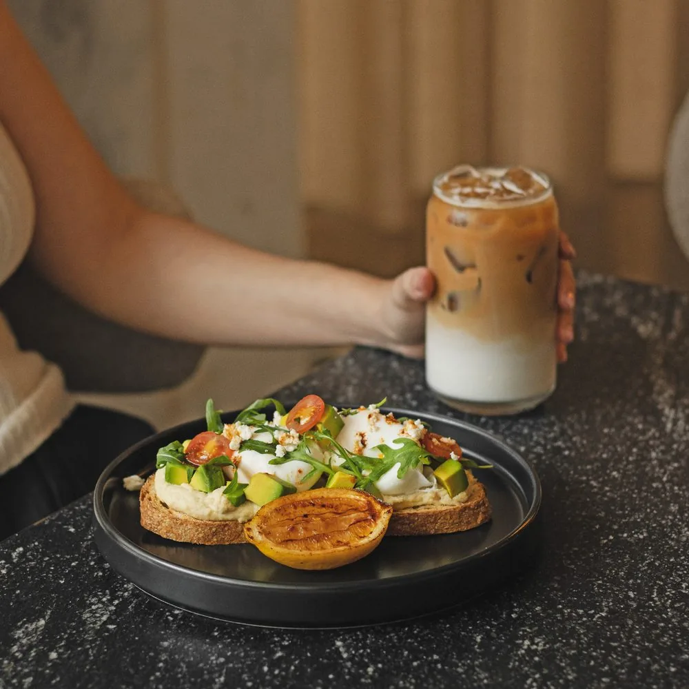 Café helado y una tosta con huevo sobre la mesa de granito