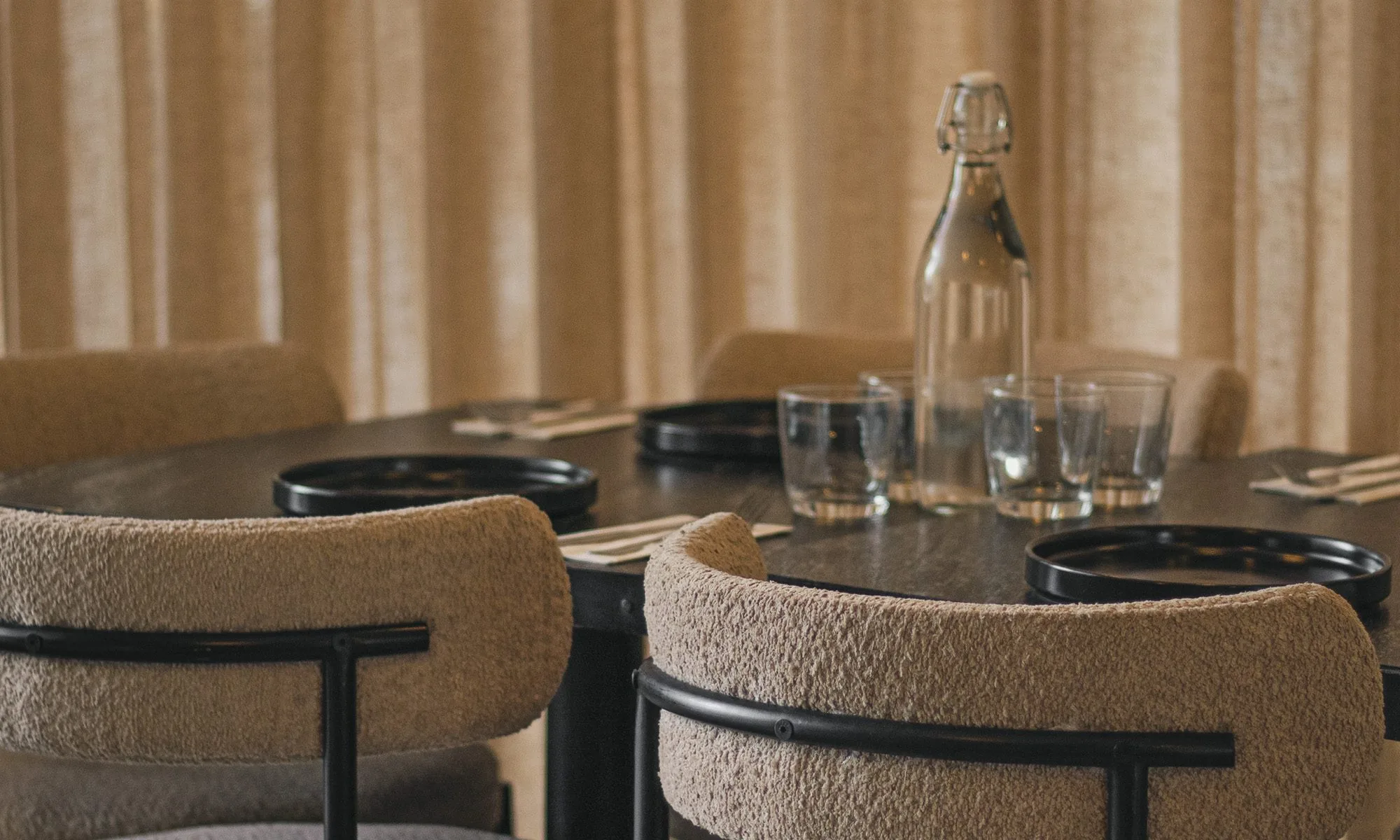 Salón de Carmela Plaza Ceiba: sillas de bouclé, mesa puesta y cortinas de lino
