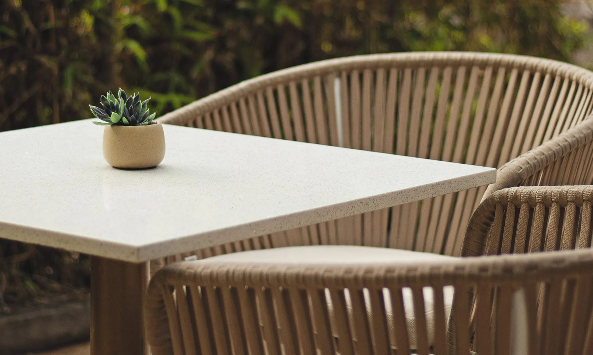 Terraza de Carmela Primavera: mesa de cuarzo con una suculenta entre sillas tejidas